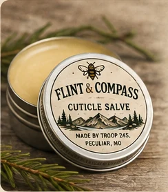 Open tin of Flint & Compass cuticle salve with its lid resting beside it, surrounded by pine needles